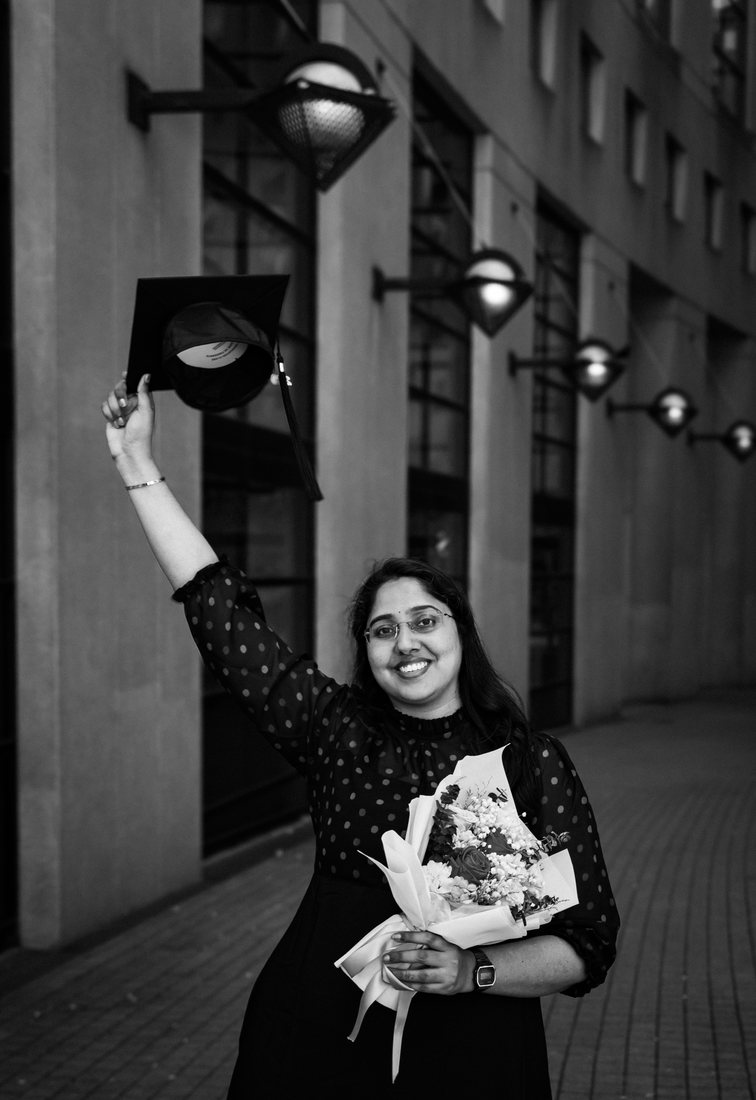 Graduate throwing her cap outside Vancouver Public Library, monochrome