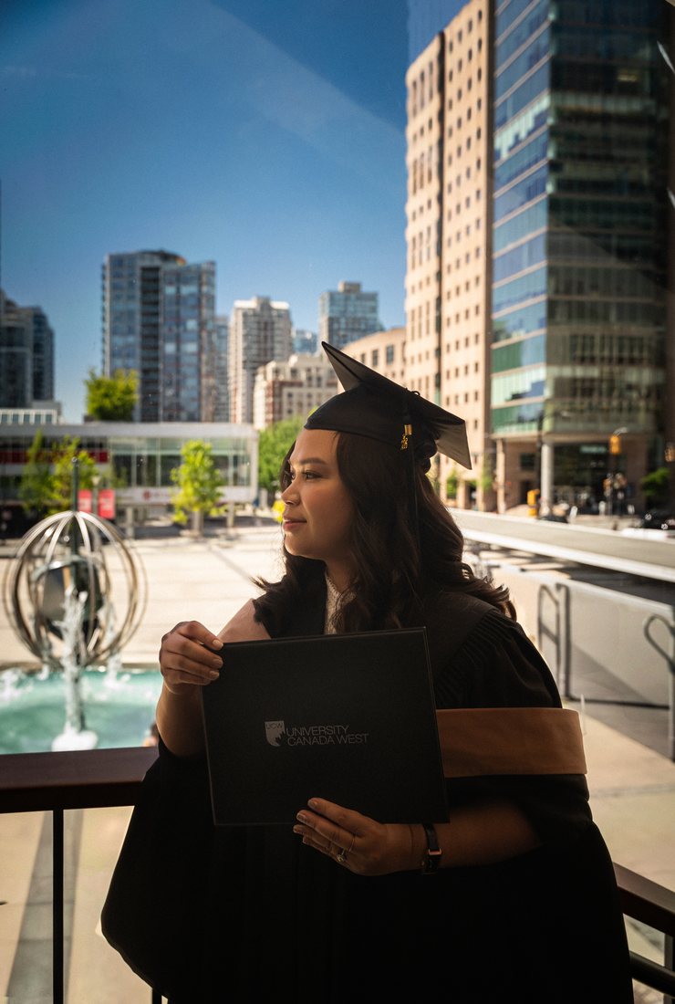 Graduate in profile at the Queen Elizabeth Theatre plaza with the fountain and downtown towers behind