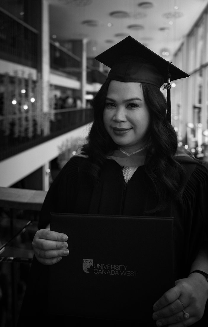 Graduate holding her degree in a theatre foyer, monochrome
